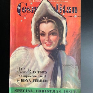 Pu&ograve; includere: Una copertina di rivista vintage con una donna in un cappotto bianco con cappuccio su uno sfondo rosso. La rivista si intitola "Cosmopolitan" e la storia di copertina &egrave; "Nobody's In Town" di Edna Ferber. La rivista &egrave; un numero speciale di Natale.