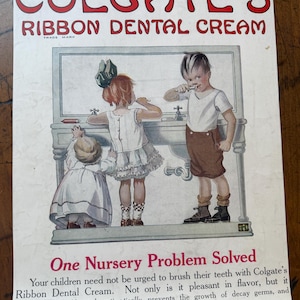 May include: Vintage advertisement for Colgate's Ribbon Dental Cream. The ad features an illustration of three children brushing their teeth at a sink. The text reads "One Nursery Problem Solved" and promotes the product's benefits.