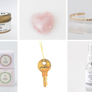 May include: A collection of self-care items including a pink heart-shaped crystal, a gold key necklace with the word "power" engraved on it, a gold bracelet with the word "Okana" engraved on it, a small candle in a gold tin with the text "Moss + Brooke Sea Salt", a bottle of pillow spray with the text "From Molly with Love Sleeping Beauty Pillow Spray", and four small bath bombs with the text "Shower Steamer" on each.