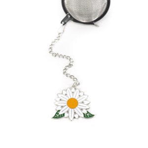 以下が含まれることがあります： チェーンとデイジーチャームが付いたシルバーのティーインフューザー。デイジーは白で、中心が黄色、葉が緑色です。