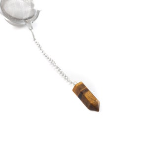 以下が含まれることがあります： チェーンと茶色のタイガーアイクリスタルペンダントが付いたシルバーのティーインフューザー