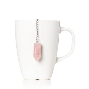 以下が含まれることがあります： 銀色のチェーンとピンクのクリスタル製のティーインフューザーが付いた白いセラミック製のマグカップ