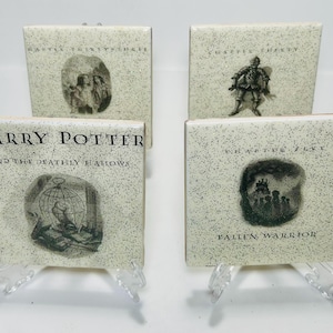 Peut inclure: Quatre carreaux en céramique carrés présentant des illustrations en noir et blanc et du texte tiré de Harry Potter et les Reliques de la Mort. Chaque carreau a un fond crème moucheté. Le texte inclut des titres de chapitres et le titre du livre.