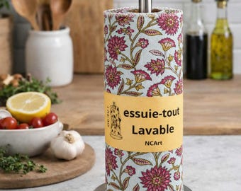 Peut inclure: Un rouleau d'essuie-tout lavable avec un fond bleu clair et un motif floral répétitif dans des tons rose et doré. Une bande de papier jaune entoure le centre avec le texte essuie-tout Lavable NCArt. Il est posé sur un support en métal.