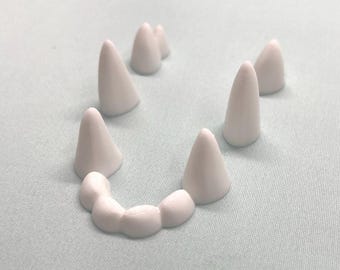May include: White plastic teeth arranged in a smile shape on a light blue background.