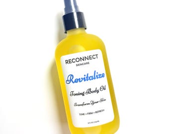 May include: A clear plastic bottle filled with bright yellow toning body oil, featuring a black spray pump nozzle. The white label reads RECONNECT SKINCARE, Revitalize, Toning Body Oil, Transform Your Skin, TONE + FIRM + REFRESH, and 8 FL OZ / 236 ML.