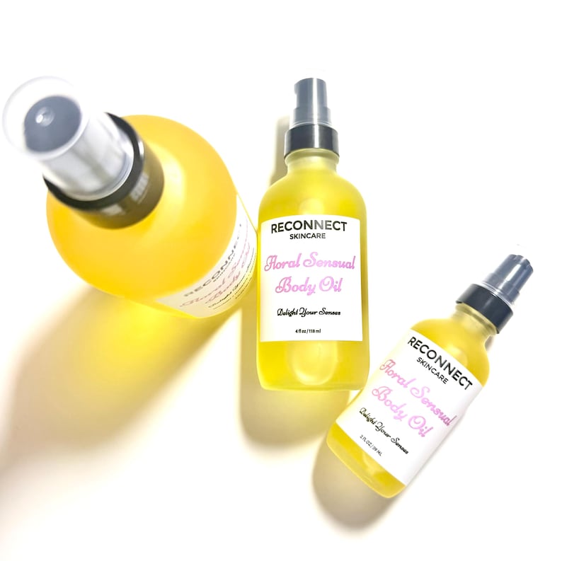 May include: Three clear glass spray bottles filled with yellow body oil. Each bottle features a white label with the text RECONNECT SKINCARE, Floral Sensual Body Oil, and Delight Your Senses. The bottles are labeled with 4 oz/118 ml and 2 oz/59 ml.