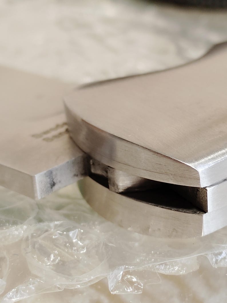 May include: Close-up of a stainless steel cleaver knife. The blade is rectangular and the handle is curved. The knife appears to be new and unused. The image is well-lit, highlighting the metallic sheen of the steel.