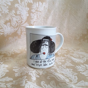 May include: White ceramic mug with a cartoon illustration of a woman wearing a hat and glasses. The mug has the text "I gave at the office, honey and 37 yrs. later, I wish I had..."
