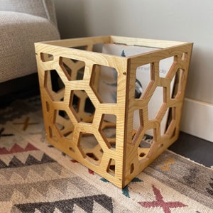 May include: A wooden record storage crate with a honeycomb pattern. The crate is made of light wood and has a natural finish.