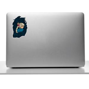 May include: A sticker depicting a cartoon illustration of a person with blonde hair and a pink bow, set against a dark blue, textured background. The person is wearing a blue top. The sticker is on a silver laptop.