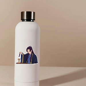 K&ouml;nnte beinhalten: Eine wei&szlig;e Wasserflasche mit silbernem Deckel. Auf der Flasche befindet sich ein Aufkleber eines Anime-Charakters in blauen und schwarzen Roben. Die Figur h&auml;lt ein kleines Objekt. Der Hintergrund ist einfarbig beige.