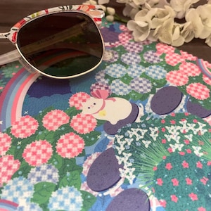 May include: A colorful microfiber cleaning cloth with a floral pattern and a rainbow design. The cloth features a white cat with a pink bow and a blue and white checkered pattern.