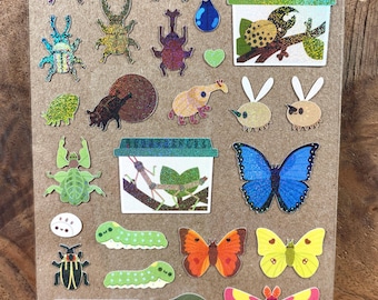 May include: A sticker sheet featuring various insects, including beetles, butterflies, moths, caterpillars, and snails. The designs include holographic and glitter finishes, with some insects depicted inside small containers on branches.