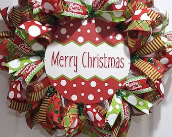 May include: A festive Christmas wreath with red and green ribbons, white polka dots, and the words "Merry Christmas" in the center. The wreath is adorned with various ribbons and decorative elements, perfect for holiday decor.