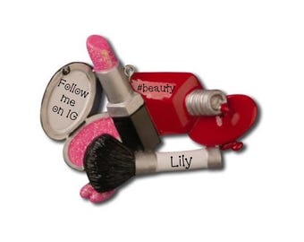 May include: A beauty-themed ornament featuring a lipstick, makeup brush, nail polish, and a compact with the text "Follow me on IG". The nail polish has the text "#beauty" and the makeup brush has the name "Lily".