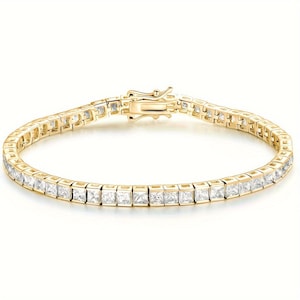May include: A gold-colored tennis bracelet with square-cut, clear gemstones. The bracelet features a secure clasp and is designed with a continuous line of stones, creating a classic and elegant look. This piece of jewelry is suitable for various occasions.