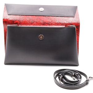 Könnte beinhalten: Schwarze und rote Clutch-Tasche mit abnehmbarem Schulterriemen. Die Tasche hat eine rote Schlangenleder-Muster-Außenseite und eine schwarze Klappe mit Magnetverschluss. Der Schulterriemen ist schwarz.