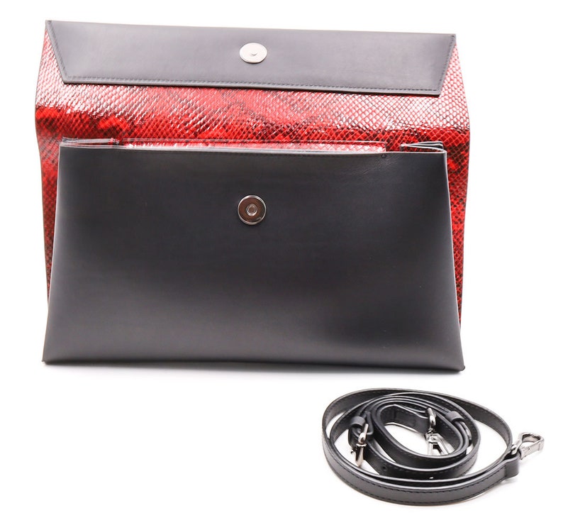 May include: A black and red clutch bag with a detachable shoulder strap. The bag has a red snakeskin-patterned exterior and a black flap with a magnetic closure. The shoulder strap is black.