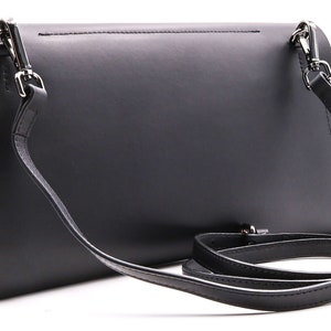 May include: Black leather crossbody bag with a detachable strap. The bag has a red and orange snakeskin-patterned interior. Silver-tone hardware accents the bag's design. The bag is rectangular and has a flap closure.