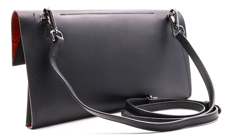 May include: Black leather crossbody bag with a detachable strap. The bag has a red and orange snakeskin-patterned interior. Silver-tone hardware accents the bag's design. The bag is rectangular and has a flap closure.