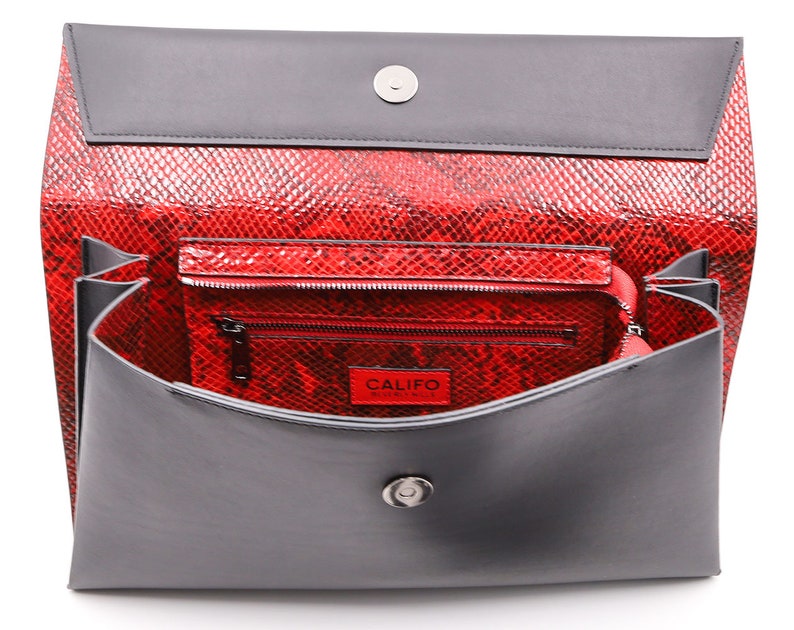 May include: A red snakeskin-effect clutch bag with a grey flap and interior. The bag contains a smaller matching wallet. The word "CALIFO" is visible on a red tag inside the wallet.