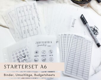 Könnte beinhalten: Ein Set transparenter A6-Starter-Set-Einsätze für Budgetierung und Finanzplanung. Enthält Budgetblätter, Sinking-Fund-Tracker und Challenge-Einsätze. Ein schwarzer Marker und Büroklammern sind ebenfalls sichtbar.