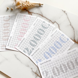 May include: Four printable sheets with a savings challenge tracker. Each sheet has a different color scheme: pink, blue, green, and gray. The sheets are labeled "Sparchallenge" and "Spare 2,000&euro;".