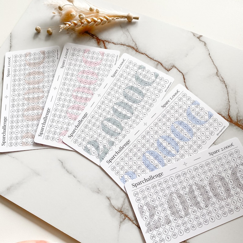 May include: Five printable charts with a light gray background and black text. Each chart has a title "Sparchallenge" and "Spare 2,000&euro;". The charts are designed to help people save money. Each chart has a grid of circles with numbers in them. The circles are filled in with different colors, including pink, blue, green, and gray.