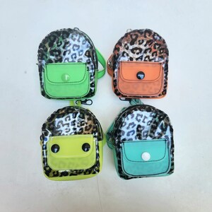 May include: Four small leopard print backpacks with clear plastic and green and orange accents. The backpacks have a small pocket on the front and a zipper closure.