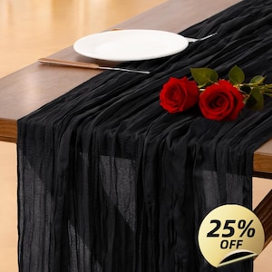 Puede incluir: Un camino de mesa negro y texturizado sobre una mesa de madera. Dos rosas rojas y un plato blanco están sobre la mesa. Un cuchillo descansa junto al plato. Una pegatina dorada con "25% OFF" está en la esquina inferior derecha.