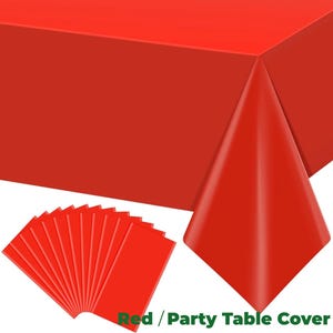 Può includere: Una tovaglia rossa brillante per feste e tovagliette rettangolari abbinate. La tovaglia è drappeggiata su un tavolo, con una parte piegata per mostrare lo spessore. Il testo "Red / Party Table Cover" è visibile.