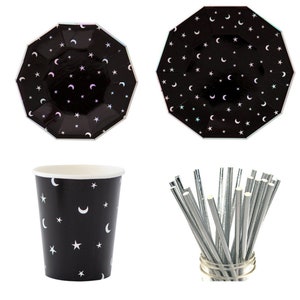 May include: A set of black and white party supplies featuring a crescent moon and star design. The set includes paper plates, cups, and silver straws.