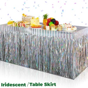 May include: A silver iridescent table skirt with a fringe design. The table is set with various desserts, including cakes, pastries, and fruit. The text "Iridescent / Table Skirt" is at the bottom of the image.