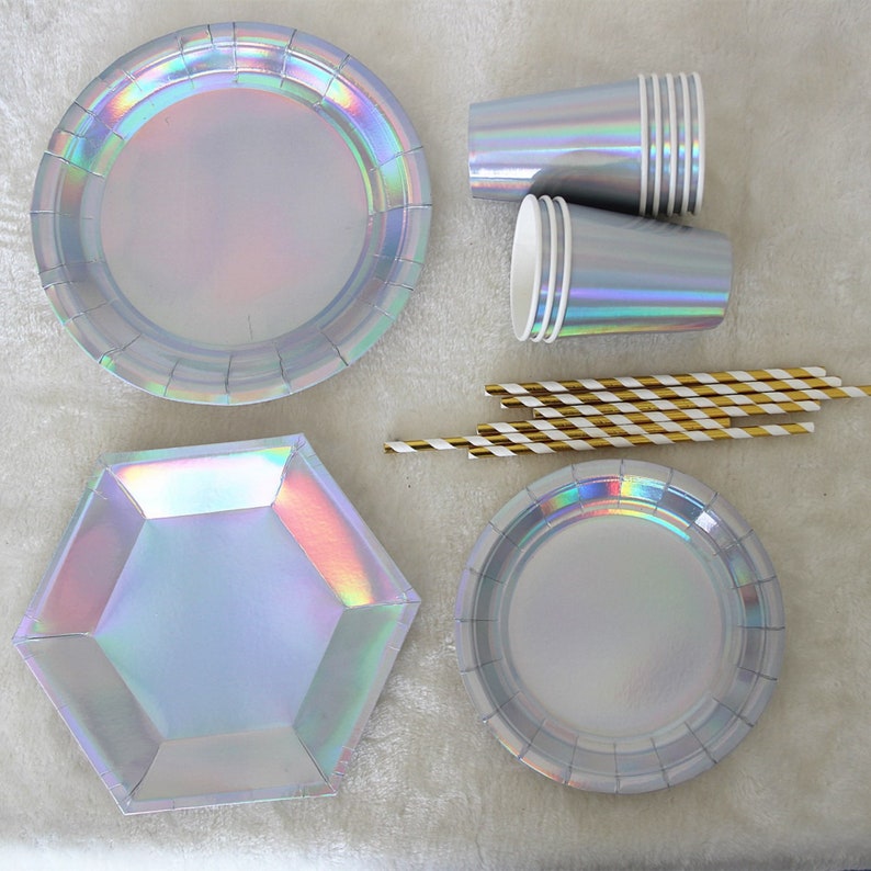 May include: A set of iridescent silver party supplies, including round and hexagonal plates, cups, and striped straws.