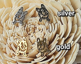 Könnte beinhalten: Zwei Paar Ohrringe mit einer Bulldoggen-Silhouette. Ein Paar ist silber und das andere gold. Die Ohrringe werden auf einer weißen Blume präsentiert.