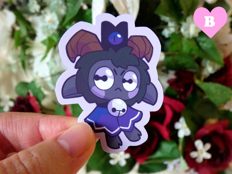 May include: A sticker featuring a cartoon black sheep with a blue crown and a purple cape. The sheep has a grumpy expression and is wearing a blue crown with a white gem.