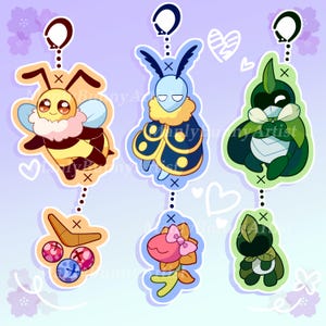 May include: Six colorful cartoon character keychains with a chain and a ring at the top. The characters include a bee, a moth, a plant, a boomerang, a flower, and a creature with a leaf on its head.