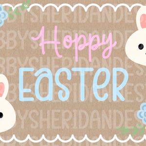 May include: A brown card with a white scalloped border features the text "Hoppy Easter" in pink and blue. Two white bunny faces with pink ears and black eyes are on the card, along with floral accents in pink, blue, and yellow.