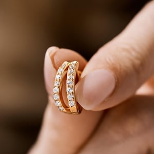 Könnte beinhalten: Ein Paar goldene Creolen mit einer Reihe kleiner Diamanten am Rand.