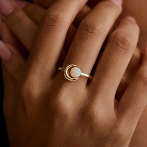 Könnte beinhalten: Ein Set aus drei Keramikbechern mit einer gesprenkelten, cremefarbenen Glasur. Jeder Becher hat ein anderes handgemaltes Design: ein blaues und grünes Blatt, eine gelbe Blume und eine rote Beere. Die Becher haben eine einfache, abgerundete Form und einen bequemen Griff.