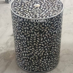May include: A round black and white side table with a floral pattern made of mother of pearl inlay. The table is about 18 inches tall and 16 inches in diameter. The table is labeled "US Crafts".