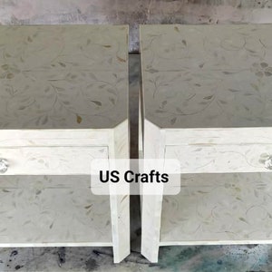 May include: Two white nightstands with a single drawer and a lower shelf. The nightstands are decorated with a floral pattern and have a crystal knob on the drawer. The text "US Crafts" is visible on the image.