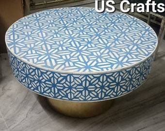 Op de afbeelding: Een ronde blauwe en witte bone inlay salontafel met een gouden basis. Het tafelblad heeft een geometrisch patroon van witte sterren op een blauwe achtergrond. De tafel is gelabeld "US Crafts".