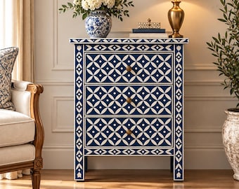 May include: A three-drawer chest featuring a deep blue finish with intricate white geometric patterns and circular motifs. The piece includes three small, round, metallic-toned knobs centered on each drawer front and a rectangular frame design.