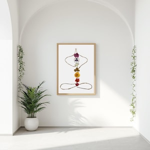 May include: A framed wall art print featuring a human figure in a seated yoga pose, constructed from thin brown twigs and seven colorful pressed flowers arranged vertically along the spine area in shades of purple, blue, white, green, yellow, orange, and red.