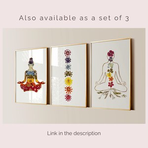 May include: Three framed wall art prints with gold borders. The left print shows a person in a seated yoga pose filled with colorful pressed flowers. The center print features a vertical column of seven pressed flowers. The right print displays a gold outline of a person in a seated pose with a vertical arrangement of pressed flowers along the spine.