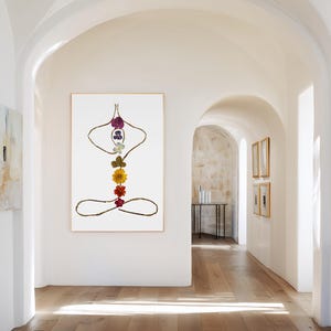 May include: A vertical rectangular wall art print featuring a stylized human figure in a seated meditation pose. The figure is outlined with thin brown twigs and decorated with seven colorful pressed flowers arranged vertically along the spine.