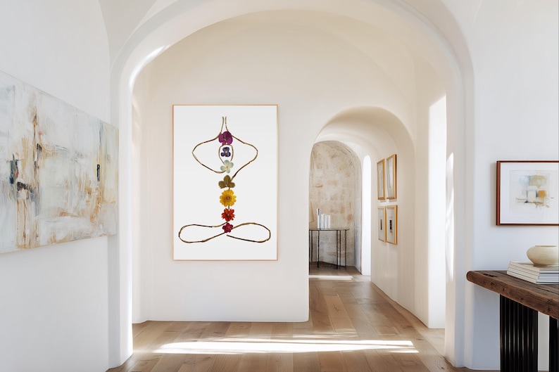 May include: A vertical rectangular wall art print featuring a stylized human figure in a seated meditation pose. The figure is outlined with thin brown twigs and decorated with seven colorful pressed flowers arranged vertically along the spine.