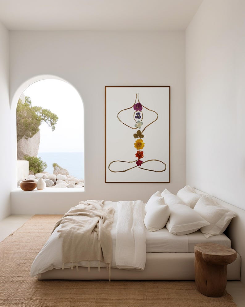 May include: A framed wall art print featuring a stylized human figure in a seated yoga pose, constructed from thin brown twigs and a vertical arrangement of seven colorful pressed flowers representing the chakras on a white background.